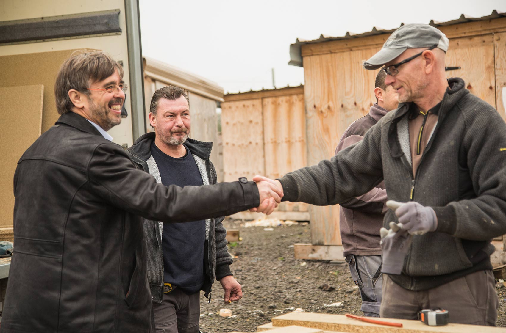 Damien Carême (à gauche), alors maire de Grande-Synthe, salue les ouvriers réparant une installation à la Linière, le premier camp construit selon les normes du Haut-commissariat aux réfugiés. Février 2017. © Lola Ledoux